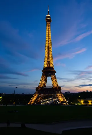 A stunning view of the Eiffel Tower at dusk, its wrought-iron lattice structure illuminated by soft golden lights, casting intricate shadows on the ground. The iconic silhouette rises against a deepening blue sky, with wisps of clouds reflecting hues of pink and orange. Surrounding the tower, the lush green lawns of Champ de Mars are dotted with picnickers and tourists, their silhouettes adding life to the scene. Nearby, the Seine River glimmers with reflections of the tower and the twinkling city lights. The intricate details of the ironwork are highlighted, showcasing the tower's elegant curves and geometric patterns. Capture this moment in a romantic, soft-focus style, evoking a sense of nostalgia and wonder, emphasizing the Eiffel Tower's timeless allure as a symbol of Parisian culture and history.